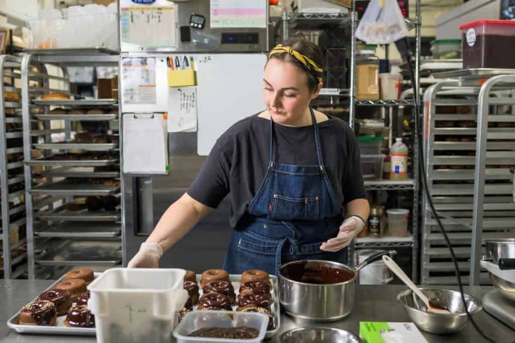 woman glazing doughnuts in bakery