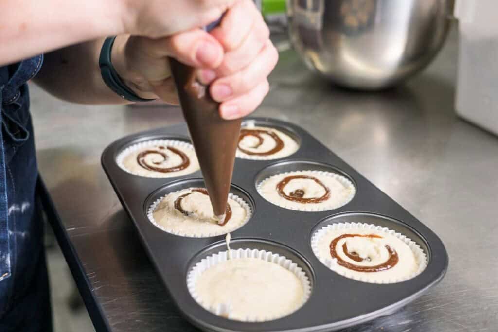 woman swirling prune butter into muffin