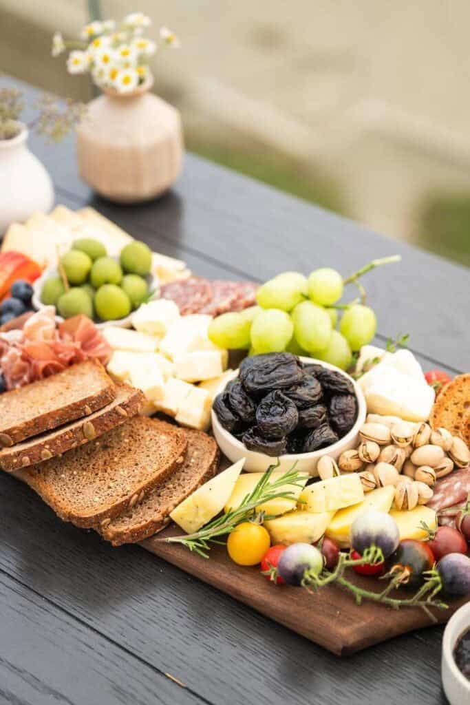 a bowl of prunes in the center of an arranged charcuterie platter